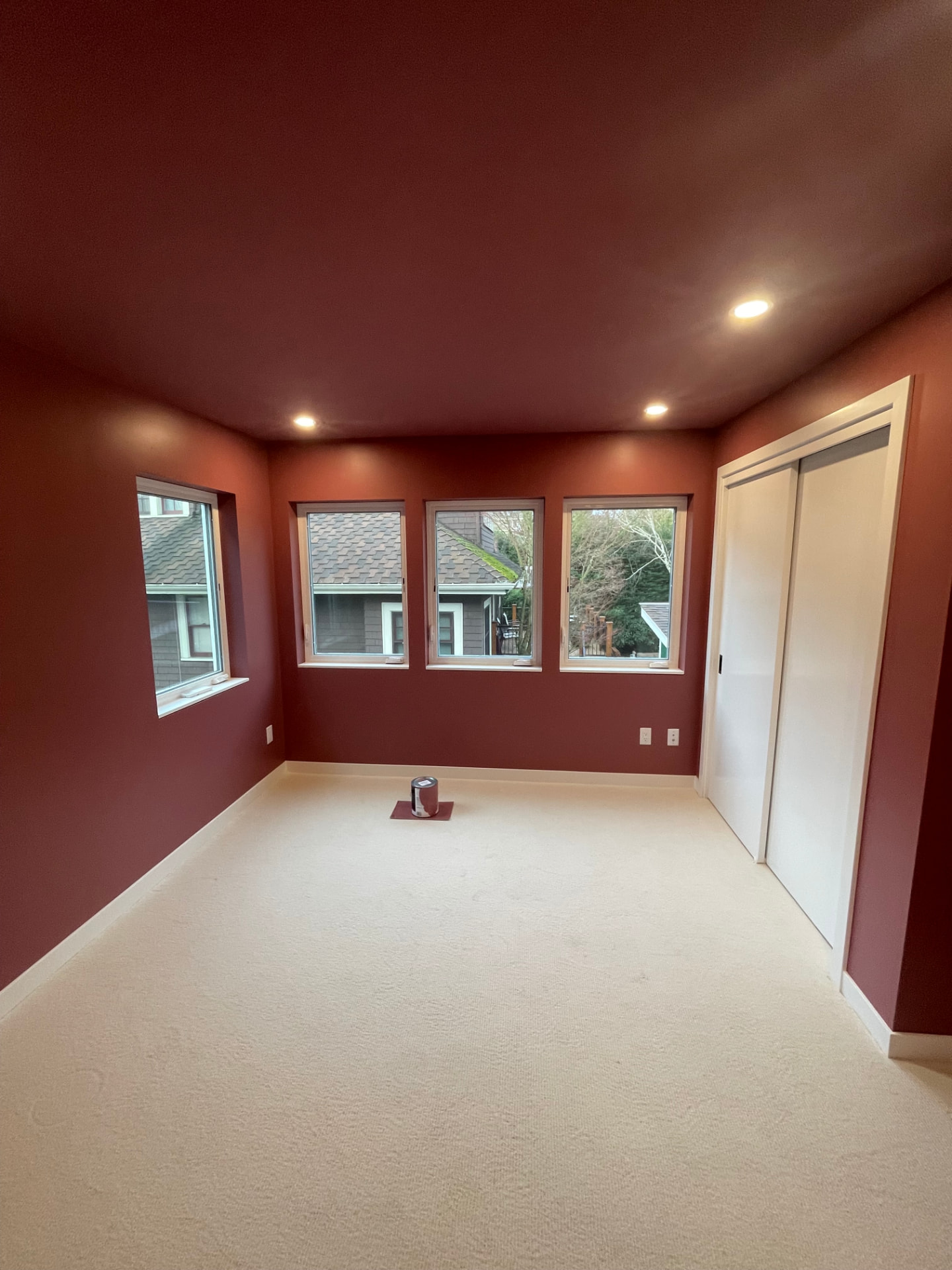 Bedroom finished in deep terracotta red with white trim and closet doors.