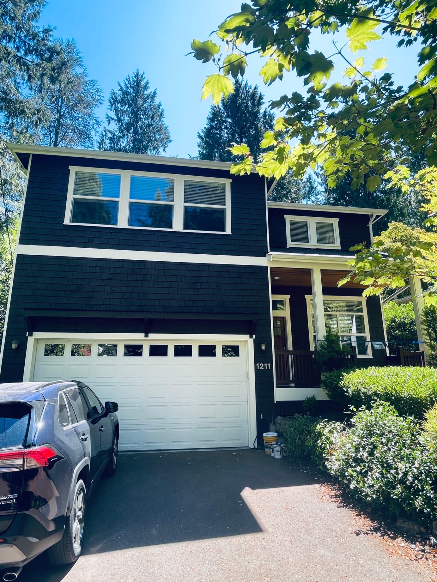 Same two-story house after repaint with dark navy siding and white trim.