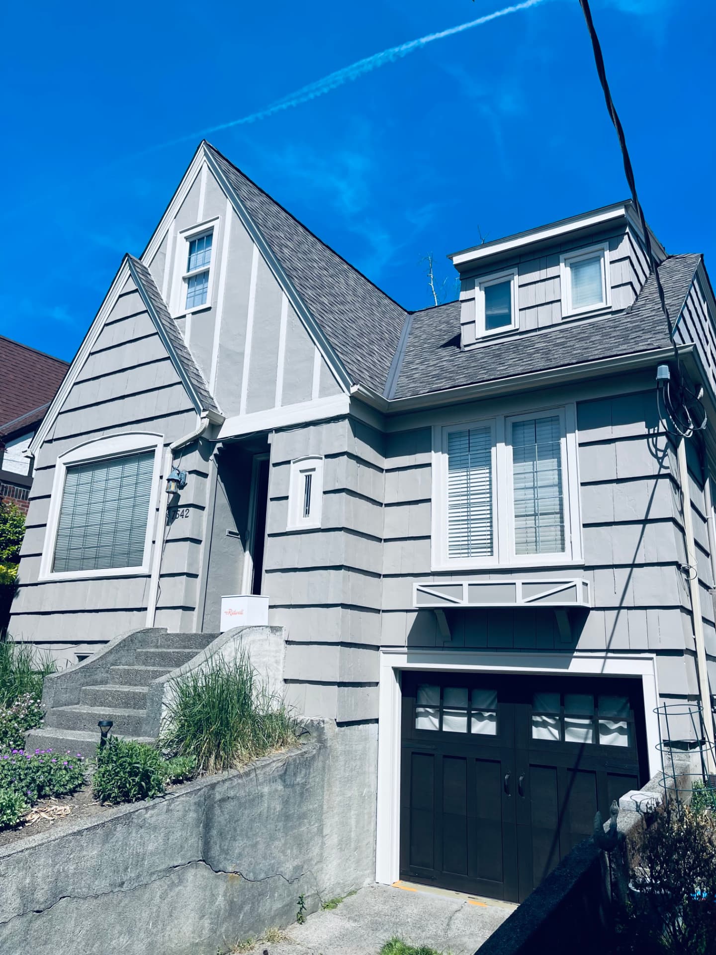 Same Tudor-style house finished in gray with white trim and a dark garage door.
