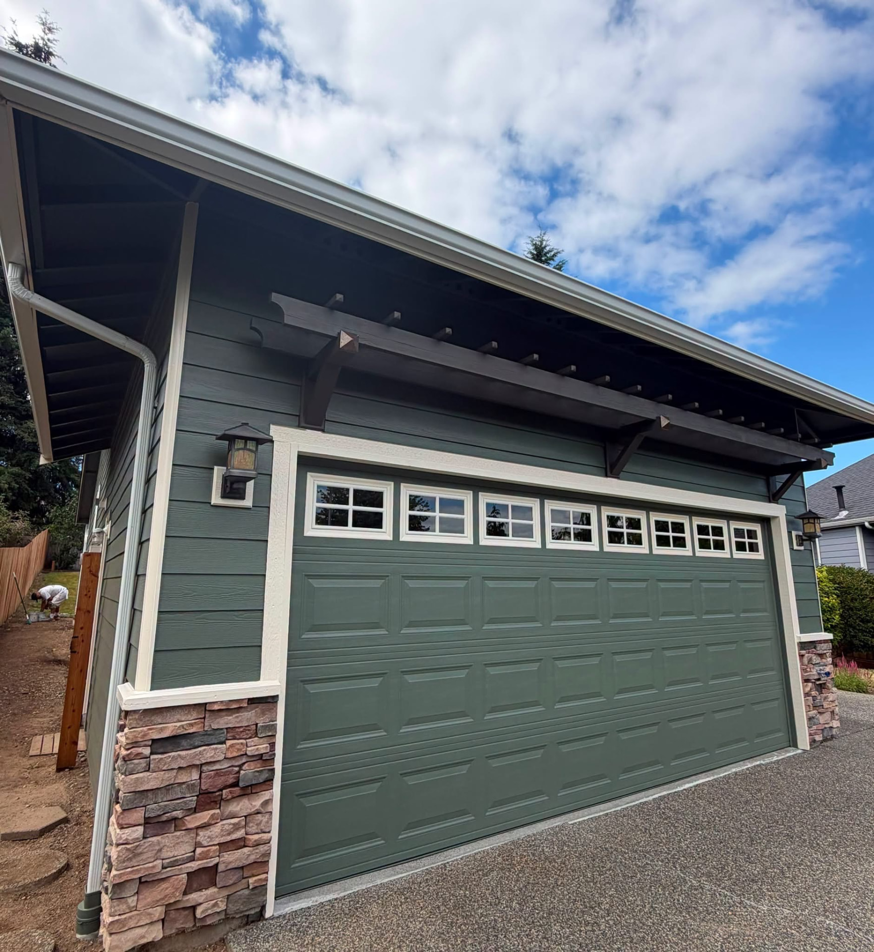 Finished garage with dark green siding and a white-trimmed door.